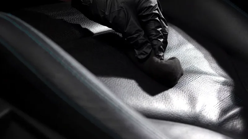 Gloved hand spreading coating across a leather seat with the foam applicator