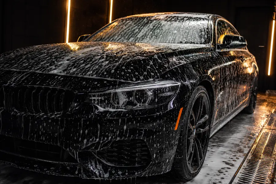 Real black performance car covered in wash foam